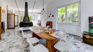 A modern dining area with a wooden table, white chairs, and a large window. - MGH Luxury - Villa Sirmione (Sirmione)