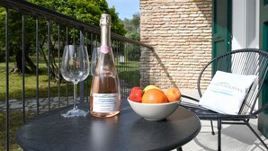 A table with a bottle of wine, a glass, and a bowl of fruit on a balcony. - MGH Luxury - Villa Sirmione (Sirmione)