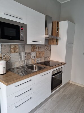 Een koelkast, een microgolfoven, een oven, kookgerei, borden en bestek