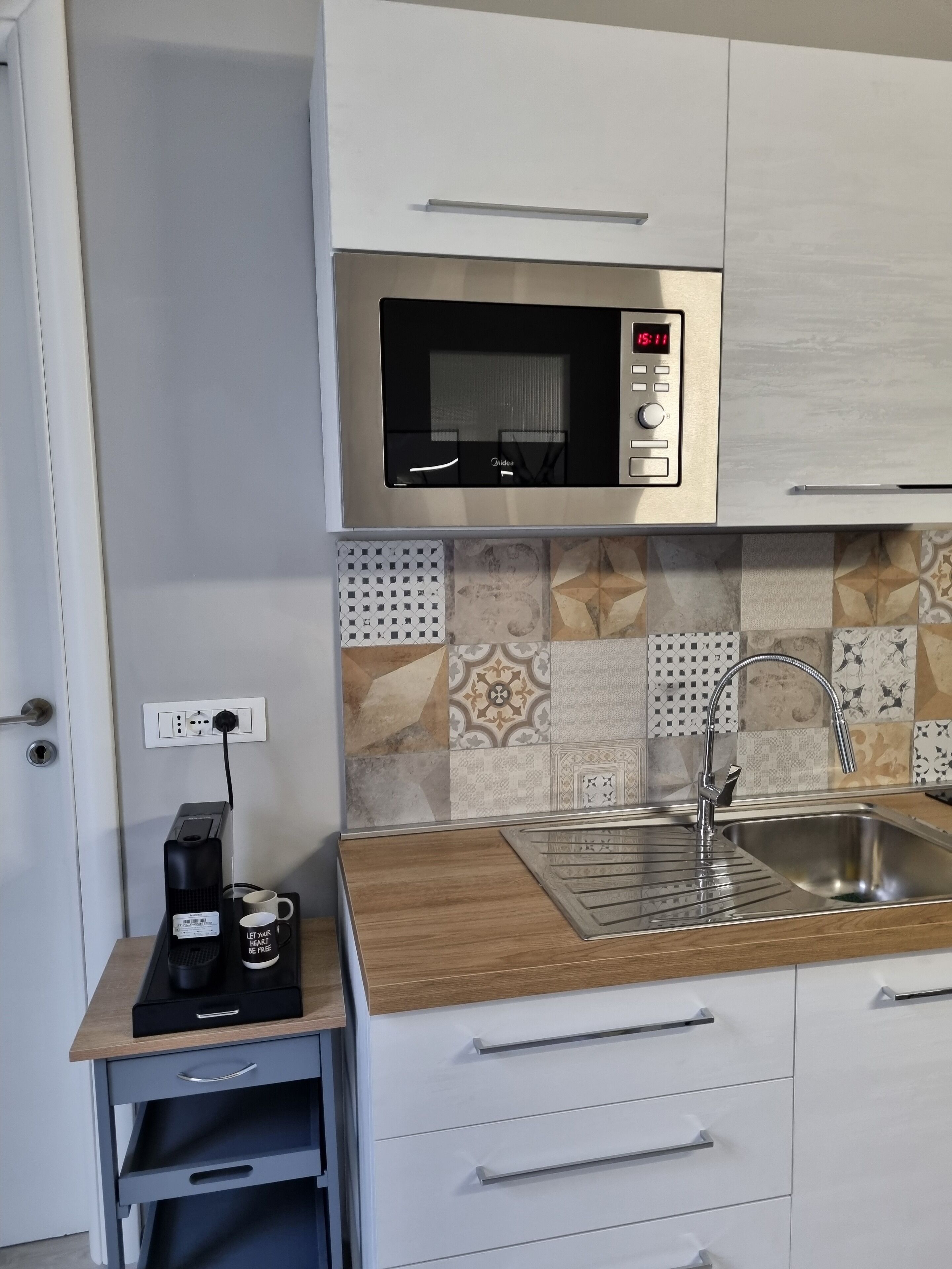 Eine kleine Küche mit einer Mikrowelle, einem Spülbecken und einer Kaffeemaschine auf einem Tisch.