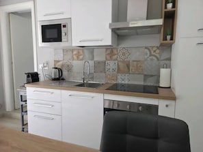 A kitchen with white cabinets, a microwave, a stove, and a sink.