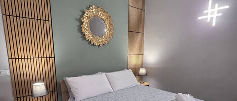 Un dormitorio moderno con una cama, mesitas de noche, una lámpara y un panel decorativo en la pared.