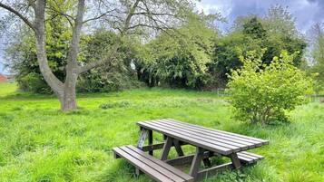 Una mesa de picnic en un área con césped, árboles y arbustos.