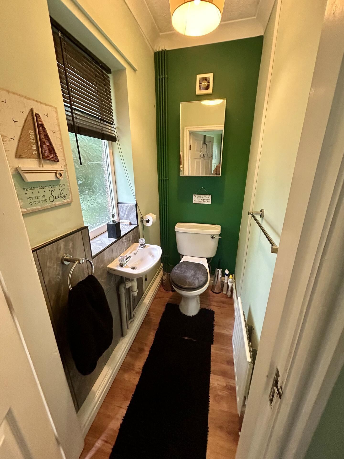A narrow bathroom with a toilet, sink, and window.