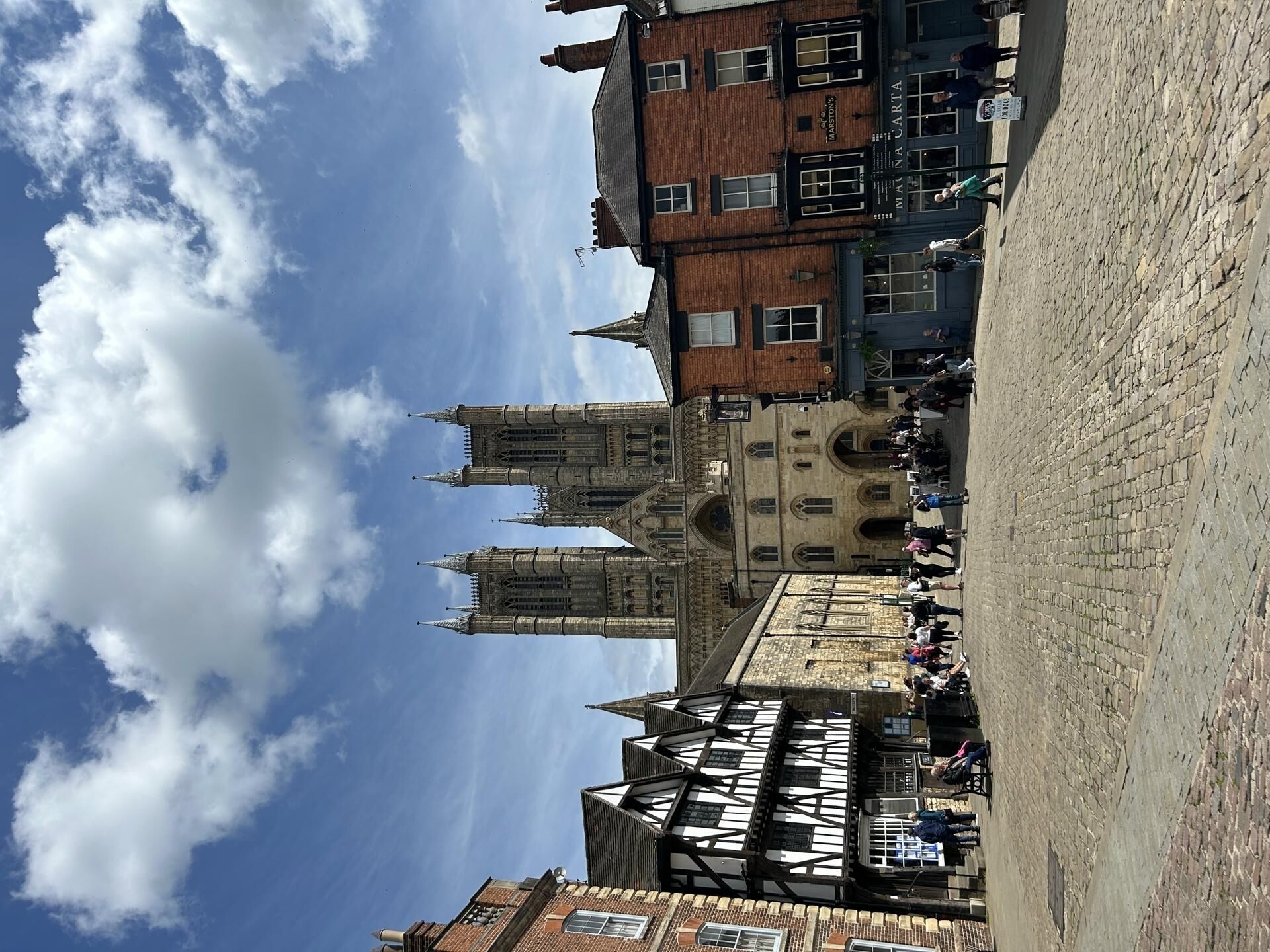 A historic building with a prominent tower and a courtyard with stone paving.