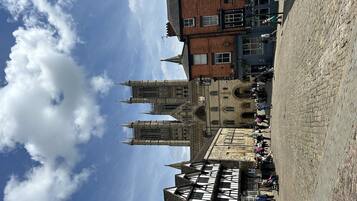 A historic building with a prominent tower and a courtyard with stone paving.