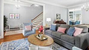 A living room with a grey sofa, blue armchair, and a wooden coffee table. - Charming Home, Victorian District (Savannah)