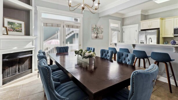 A dining room with a large rectangular table, blue upholstered chairs, a chandelier, and a fireplace. - Charming Home, Victorian District (Savannah)