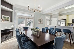A dining room with a large rectangular table, blue upholstered chairs, a chandelier, and a fireplace. - Charming Home, Victorian District (Savannah)