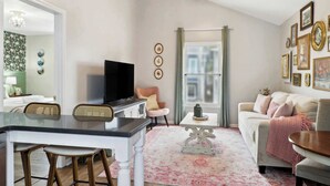 A living room with a television, a sofa, a coffee table, and a dining area with chairs. - Charming Home, Victorian District (Savannah)