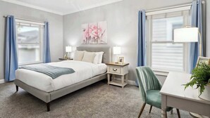 A bedroom with a bed, bedside tables, a desk, and a chair. - Charming Home, Victorian District (Savannah)