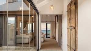 Un pasillo que da a un dormitorio con vistas al mar, una puerta de cristal y una puerta de madera.