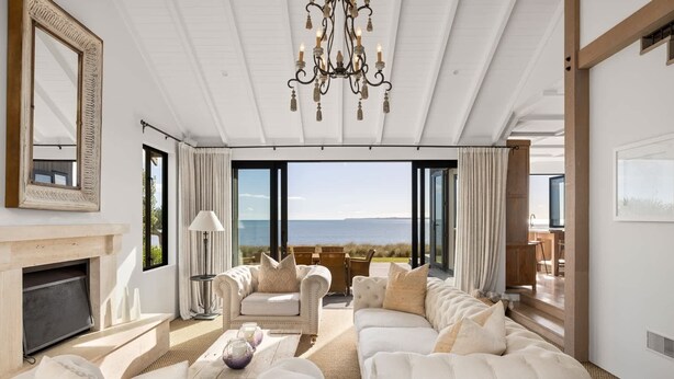 Un salón amplio con un sofá grande, una chimenea y vista al mar.