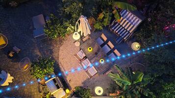Un espace extérieur aménagé en terrasse, avec des sièges, des guirlandes lumineuses et une végétation luxuriante.
