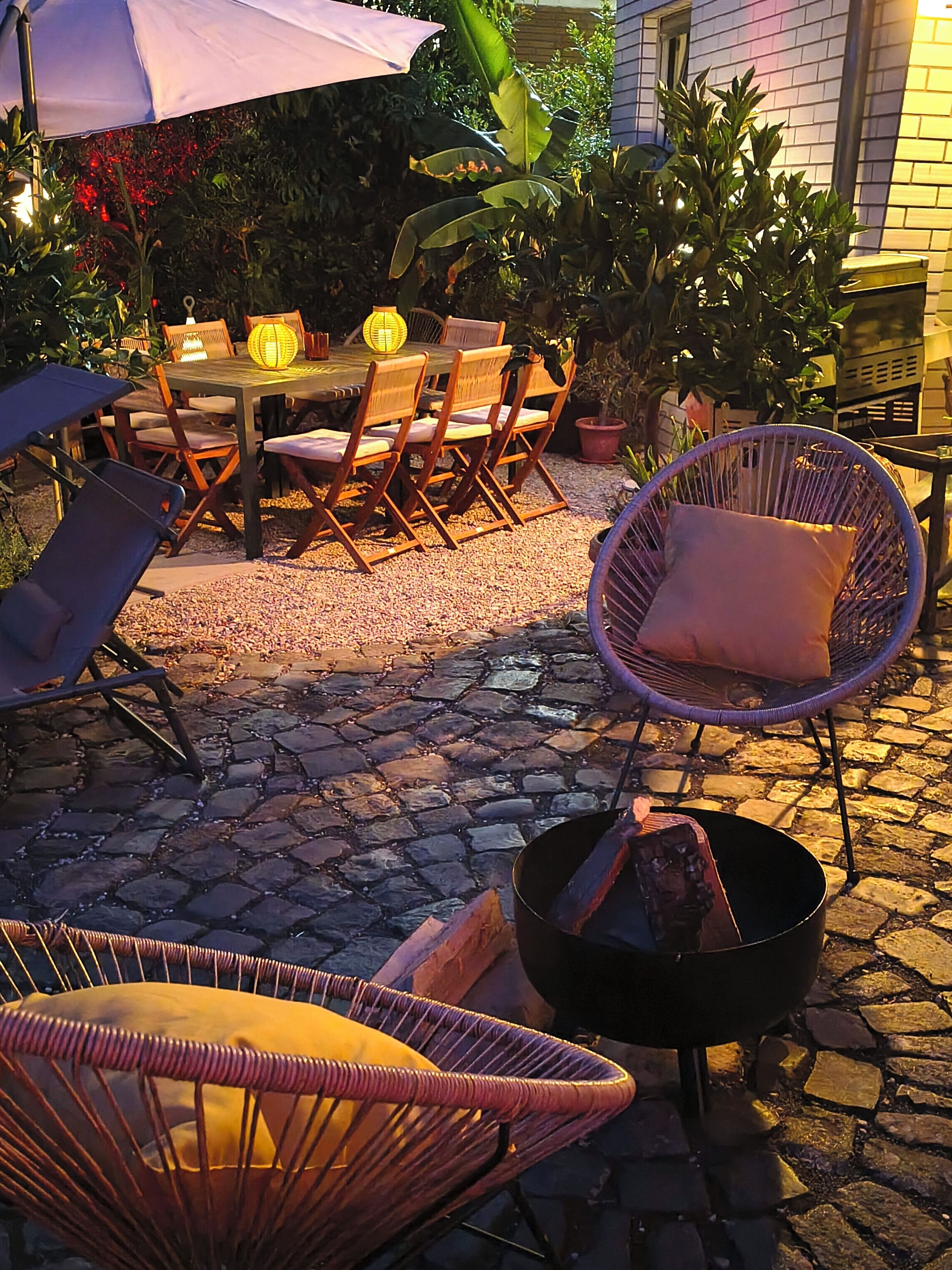 An outdoor patio area with a table and chairs, a wicker chair, and a fire pit.