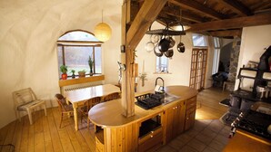 Cocina rústica con vigas de madera, una isla de madera y una pared de piedra.
