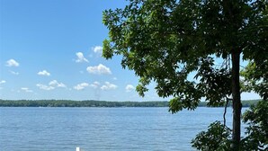 Une maison située au bord de l’eau, dotée d’une terrasse, d’un escalier et offrant une vue sur le lac.