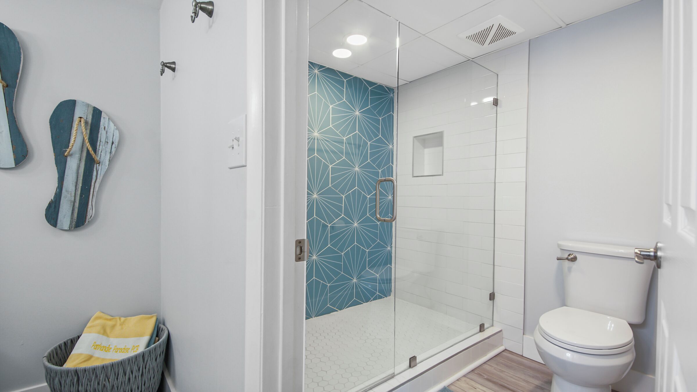 A modern bathroom with a glass-enclosed shower, white tiled walls, and a toilet.