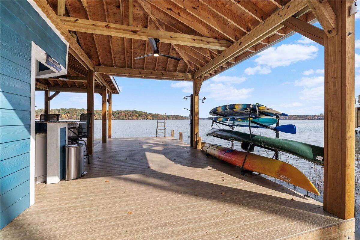 A covered deck with a view of the water, a kayak rack, and a small outdoor kitchen area.