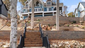 Une maison à plusieurs étages, dotée d’un escalier imposant qui mène à un porche à l’avant.