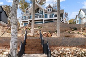A multi-story house with a prominent staircase leading to a front porch.