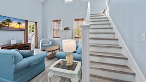 Un salon spacieux avec un canapé bleu, une table basse et un escalier.