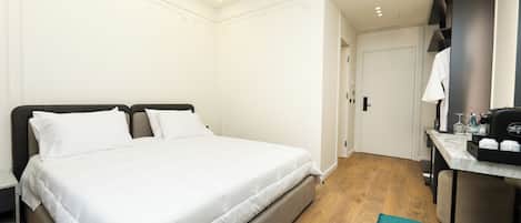 A hotel room with a bed, a desk, and a bathroom visible through an open door.