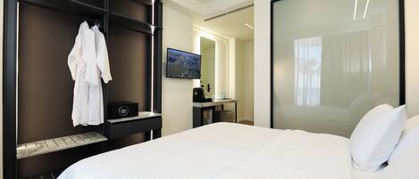 Une chambre d’hôtel moderne, dotée d’un grand lit, d’une armoire, d’un bureau avec un ordinateur et d’un téléviseur fixé au mur.