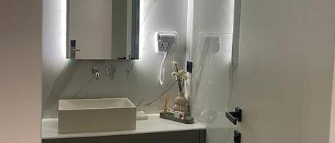 A modern bathroom with a white vanity, a large mirror, and a toilet.