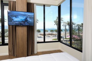 Ein Hotelzimmer mit großem Fenster, einem Flachbildfernseher an der Wand und einem Bett.