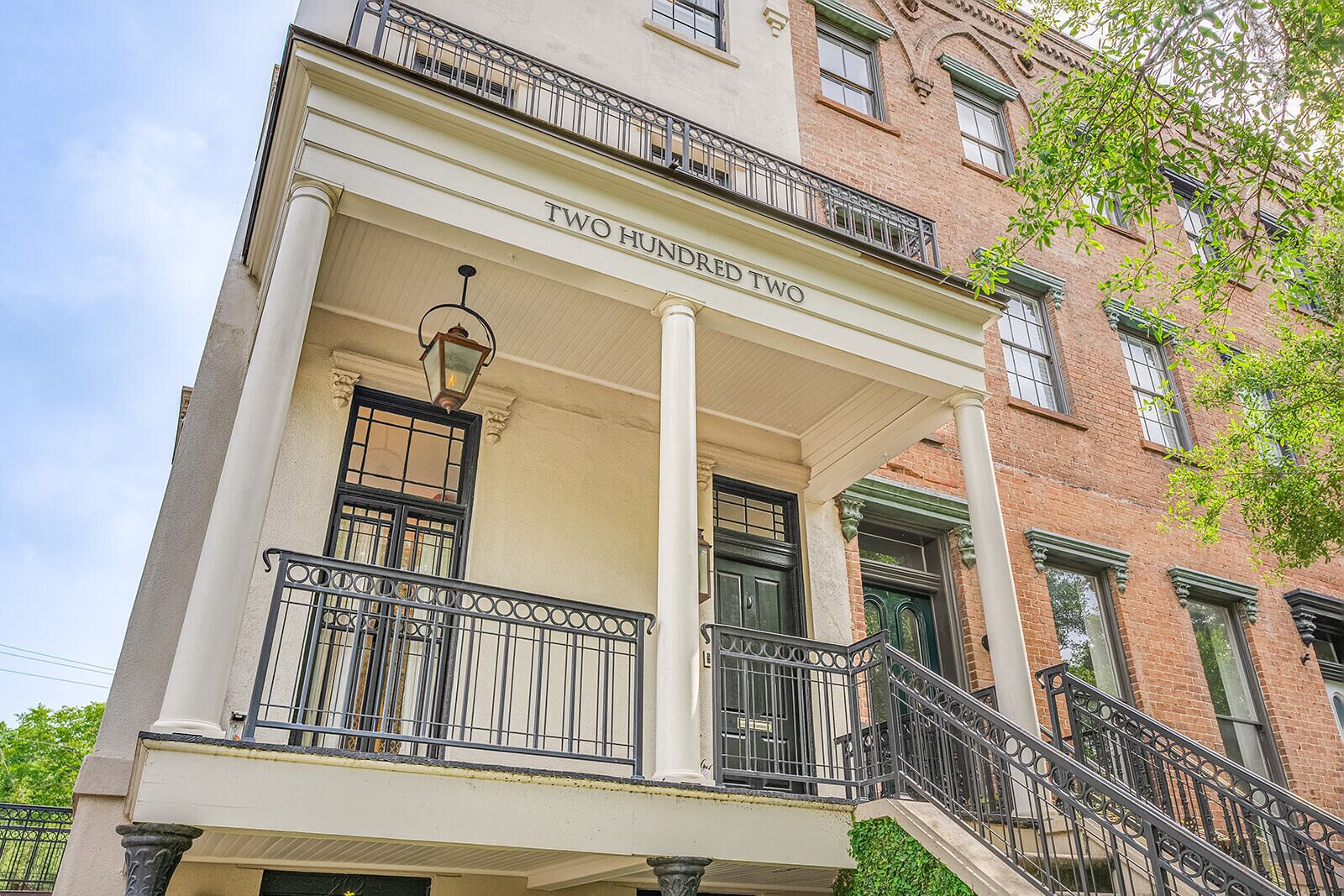 A building with a two-story balcony, a sign reading "TWO HUNDRED TWO", and a street-level entrance.