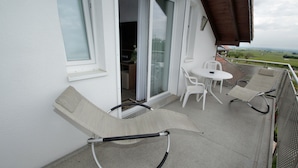 A balcony with a hammock, a table, and chairs. - Weinhotel Kienle (Burrweiler)