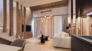 Een moderne woonkamer met een bank, een eettafel en een televisie. Er is een houten plafond en een hanglamp.
