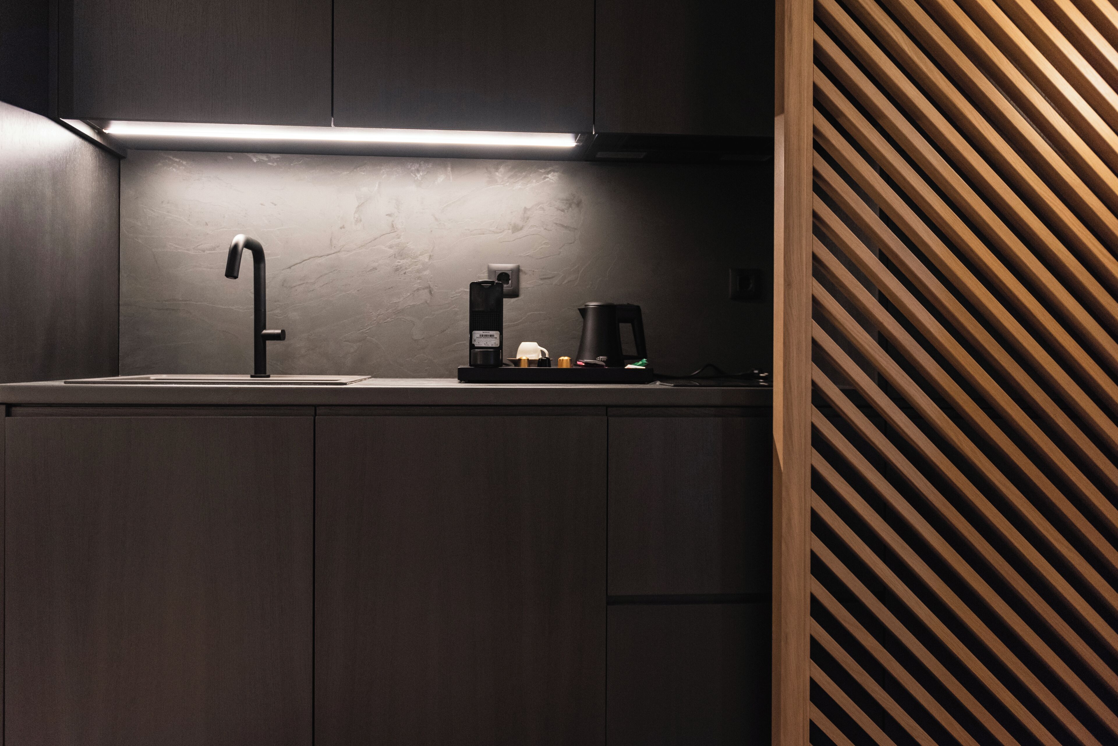 A modern kitchen with a dark wood cabinet, a black faucet, and a coffee maker on the countertop.
