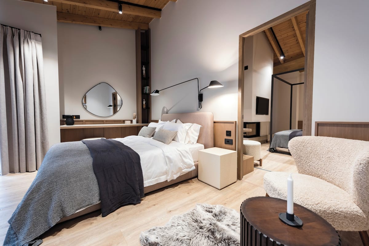 A modern bedroom with a bed, bedside tables, a mirror, a lamp, and a cozy seating area.