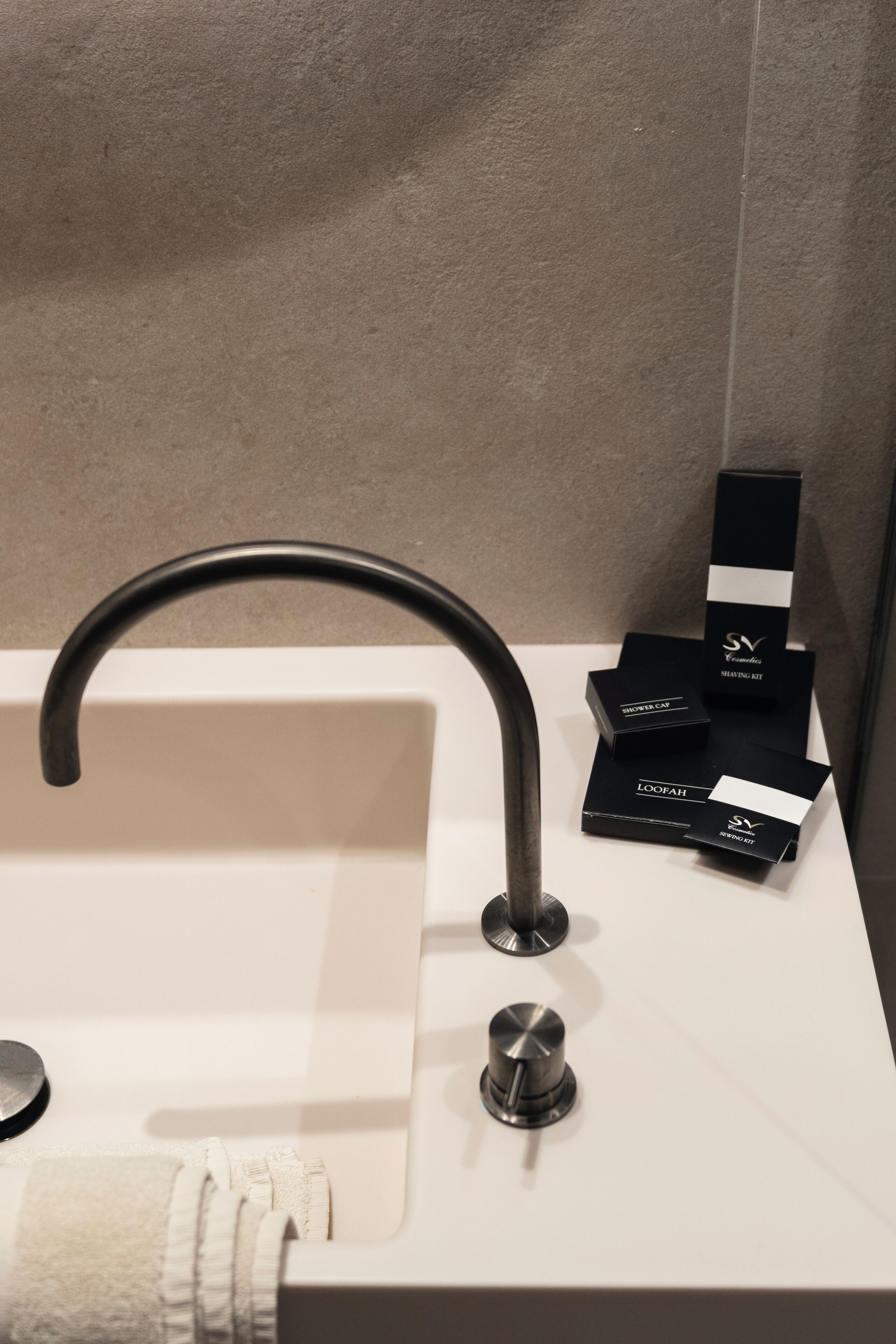 A modern bathroom with a white sink, a curved faucet, and a towel rack.