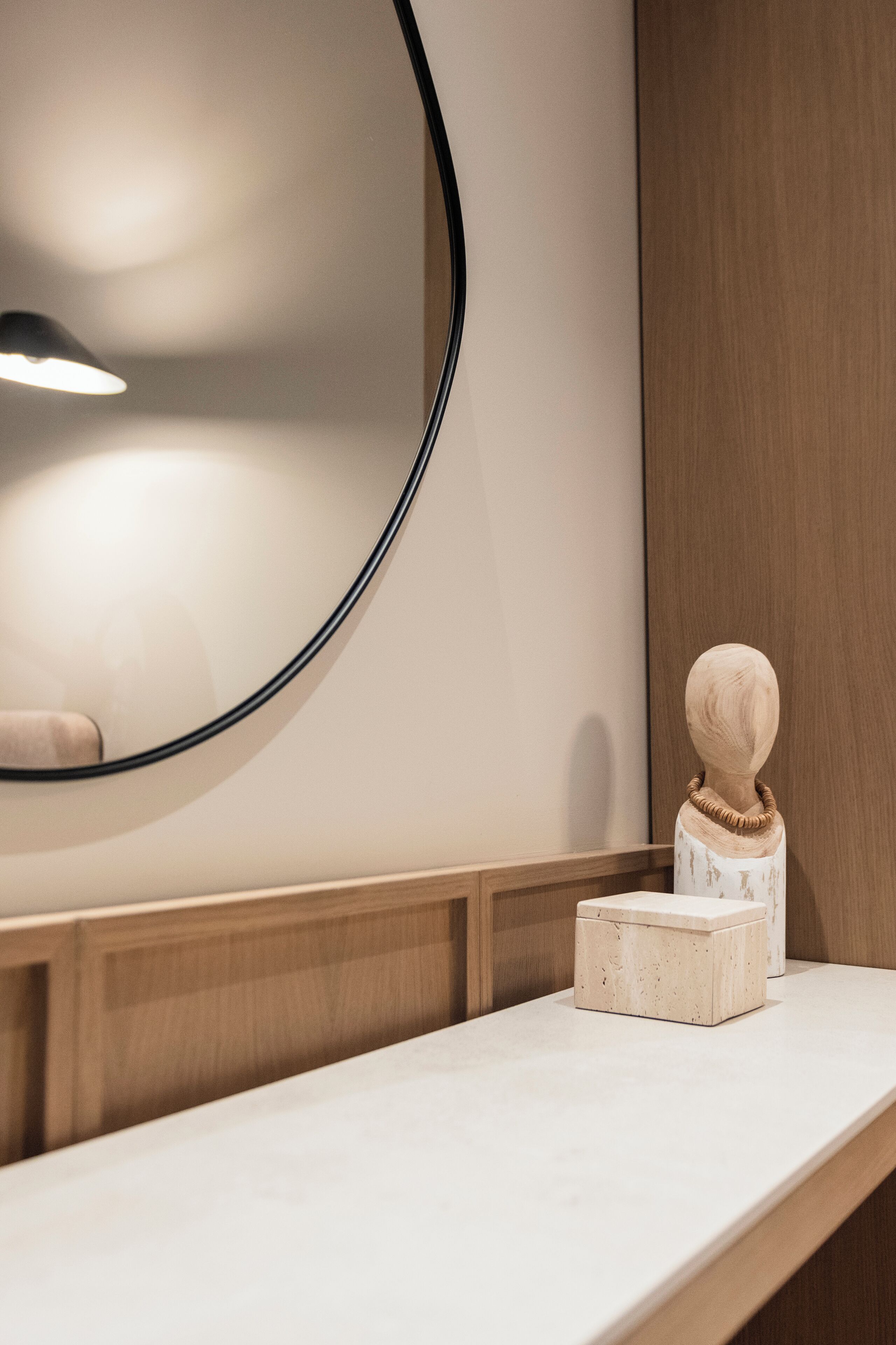 Un tocador de baño con espejo, un mueble de madera y un pequeño adorno en la encimera.