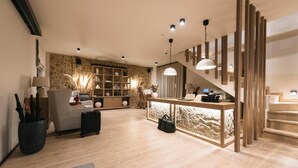 Een moderne woonkamer met een stenen accentmuur, een bank, een salontafel en een trap.