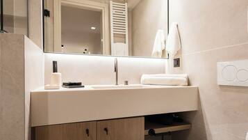 Une salle de bain moderne avec un grand miroir, un lavabo blanc, des meubles en bois, des toilettes et un porte-serviettes.