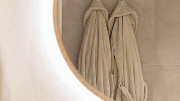 A circular mirror reflecting two towels hanging on hooks.