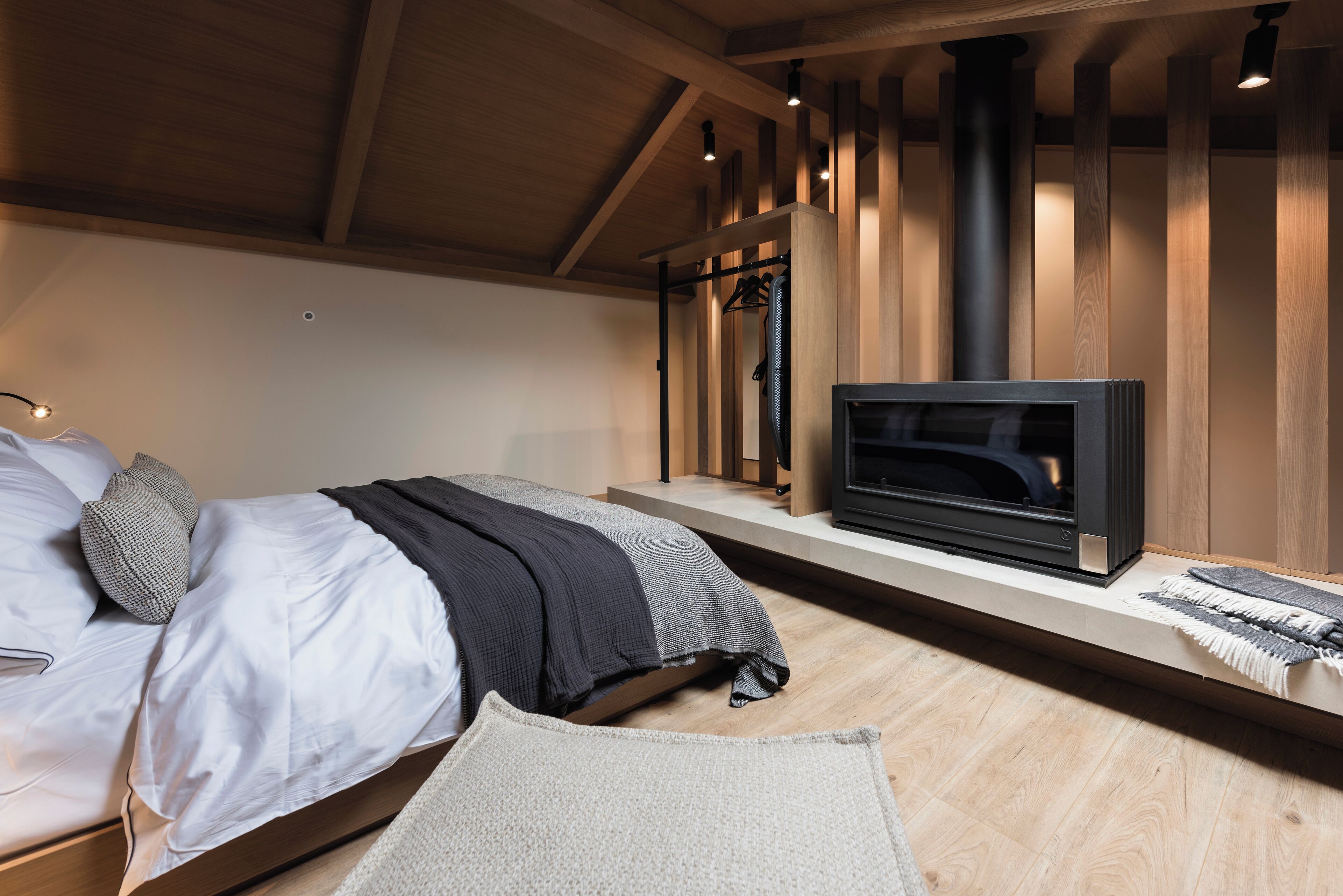 A bedroom with a bed, a TV, a heater, and a wooden ceiling.