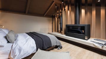 A bedroom with a bed, a TV, a heater, and a wooden ceiling.