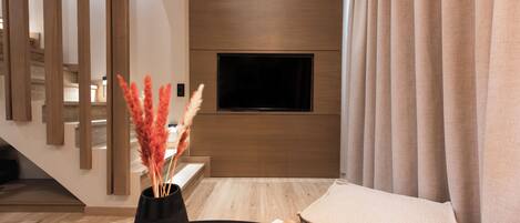 A modern living room with a black table, a vase with dried flowers, and a stack of books.