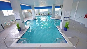 Ein hallenbad mit klarem Wasser, umgeben von weißen Wänden und blauen Akzenten, ohne sichtbare Personen oder Dekorationen.