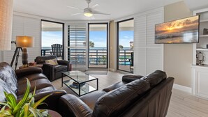 Ein modernes Wohnzimmer mit einer Ledersofa, einem Glastisch und einem Deckenventilator.