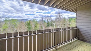 A balcony with a view of trees and hills under a cloudy sky.