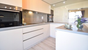 A modern kitchen with white cabinets, a Bosch oven, and a countertop with a vase of flowers.