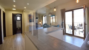 A modern interior with a kitchen area, dining space, and a balcony with outdoor seating.