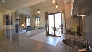 A modern kitchen with a stainless steel sink, a dining area with a table and chairs, and a large sliding glass door leading to an outdoor patio.