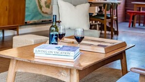 Ein gemütliches Wohnzimmer mit einem Holztisch, Büchern, Weingläsern und einem Globus.